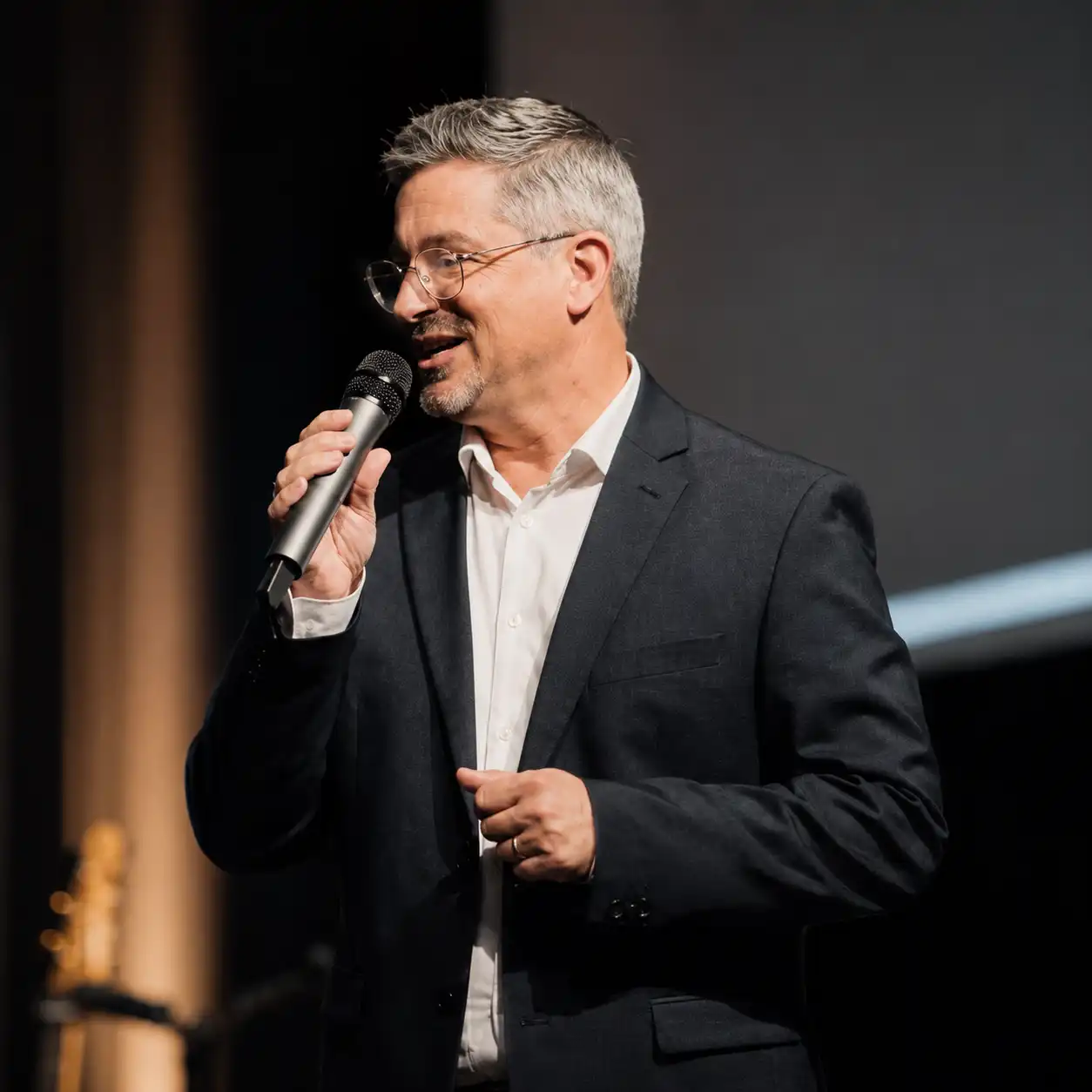 Xavier Dufour micro à la main enseignant à une foule sur scène lors d'un séminaire